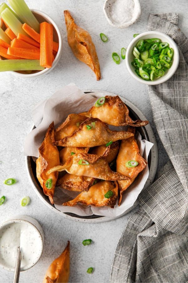 Buffalo Chicken Wontons served in a small bowl with green onions for garnishing.