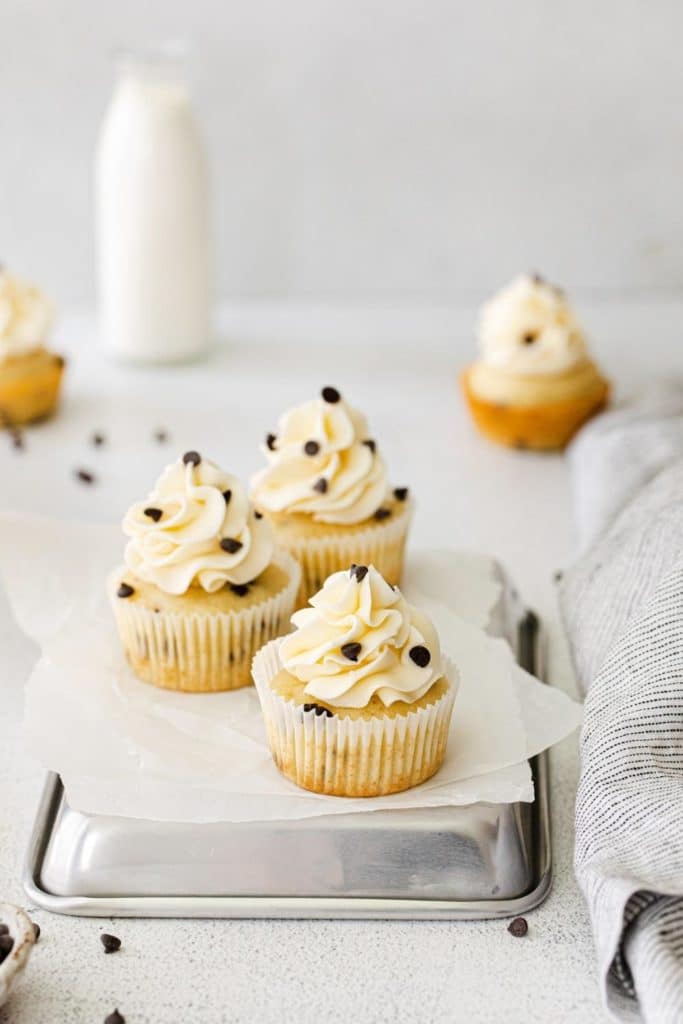 White chocolate chip cupcakes with swirls of vanilla frosting and mini chocolate chips.