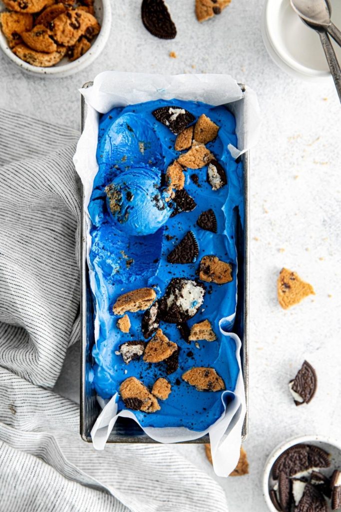Blue cookie monster ice cream in metal pan with pieces of Oreos and Chips Ahoy cookies.
