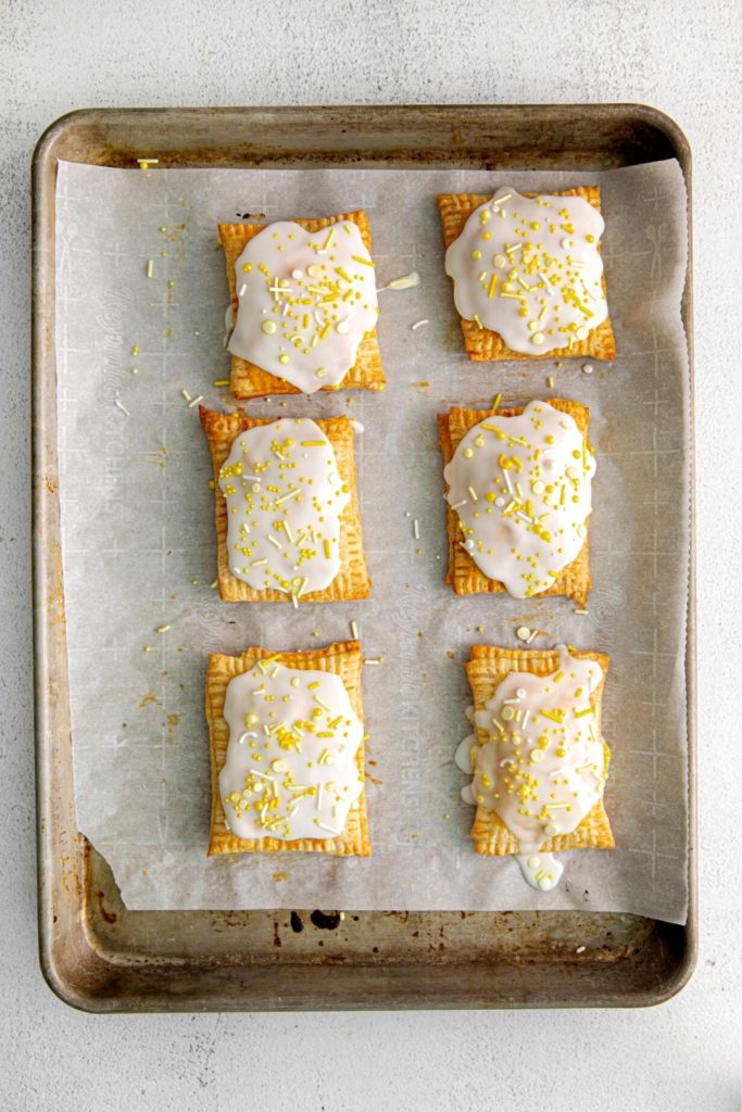 Baking tray with lemon pop tarts cooled, frosted and decorated with sprinkle mix.