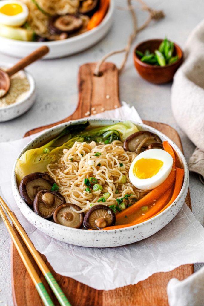 Ramen noodle bowl with mushrooms, baby bok choy, matchstick carrots, and soft-boiled egg.