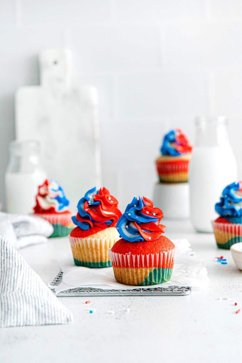4th of July Cupcakes on a dessert table with glass bottles of milk.