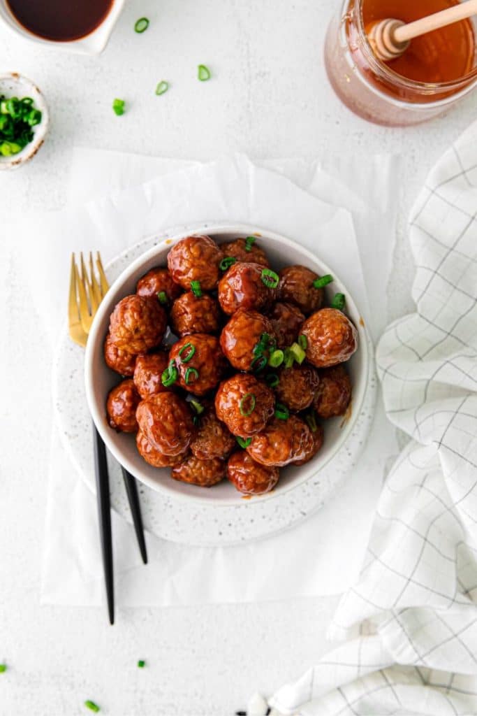 Slow Cooker Meatballs with honey BBQ glaze, sprinkled with sliced green onions.