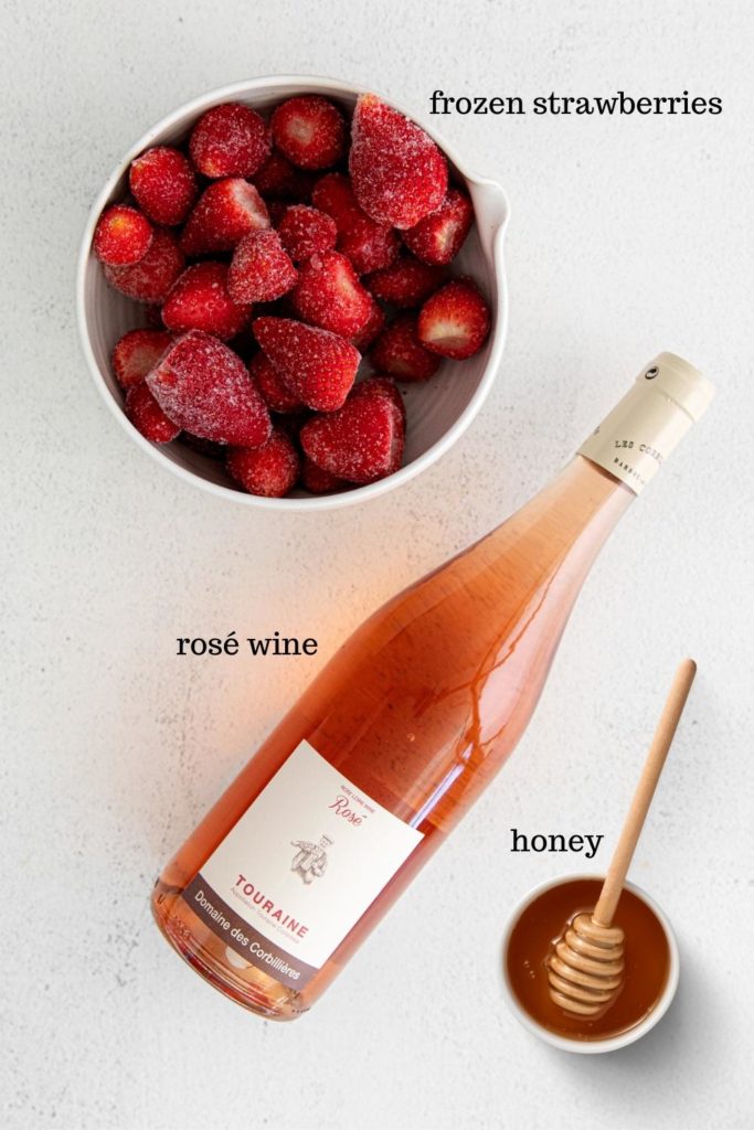 Three ingredients for frozen rosé: frozen strawberries, rosé wine, and honey.