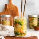 Chopsticks inside mason jar instant noodle soup prepped with ramen, veggies and savory spices.