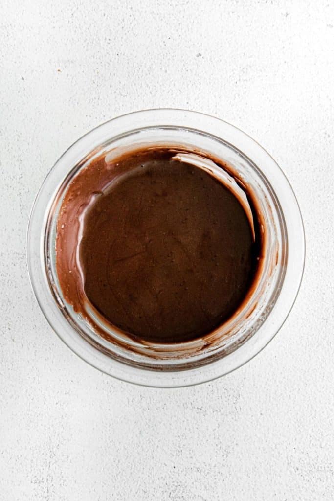 Glass jar with homemade chocolate sauce for glazing chocolate fudge pop tarts.