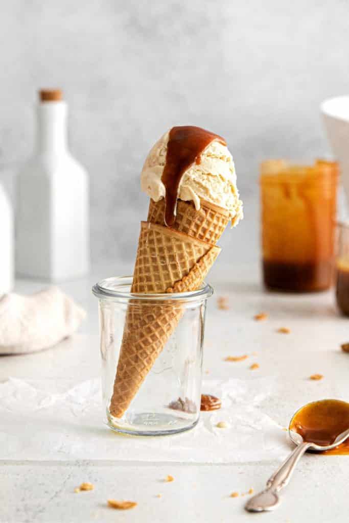Vanilla Caramel Ice Cream in a waffle cone with a thick drizzle of sea salt caramel sauce on top.