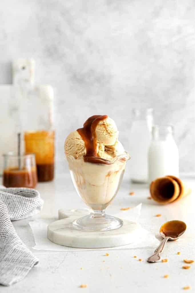Glass dessert dish with vanilla ice cream with salted caramel swirl.