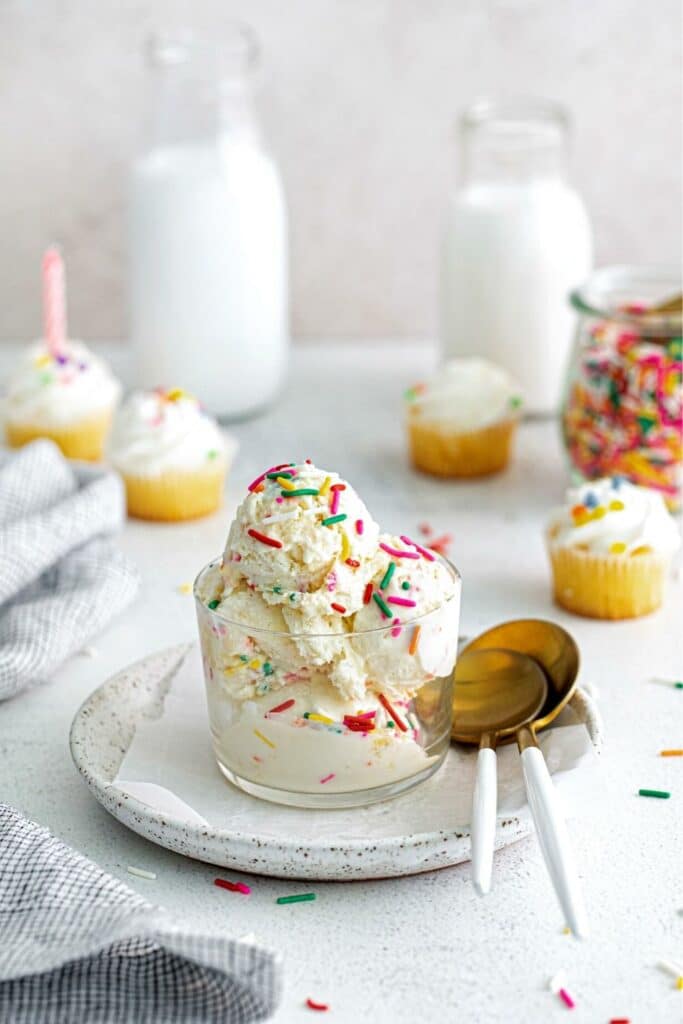 Cake batter ice cream with funfetti sprinkles served in a small glass dessert cup with spoons.