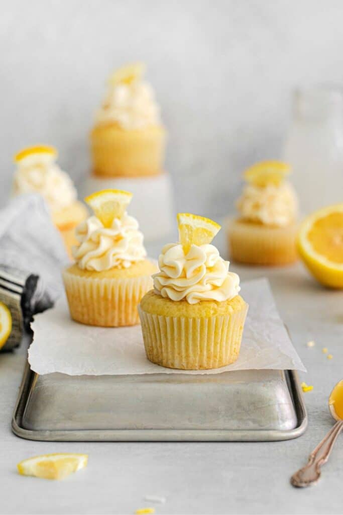 Fresh batch of lemon curd cupcakes on an upside down metal baking tray.