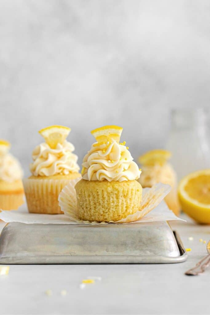 Unwrapped frosted lemon cupcake on an upside down metal tray.
