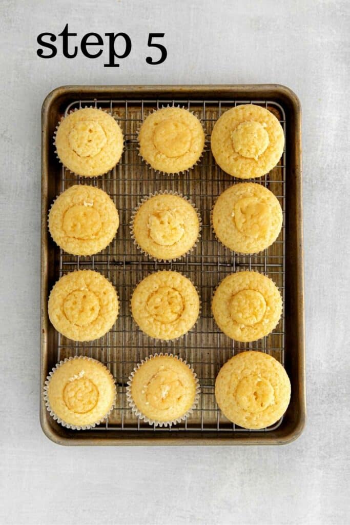 One dozen lemon-filled cupcakes with top cake pieces put back on to cover lemon curd.