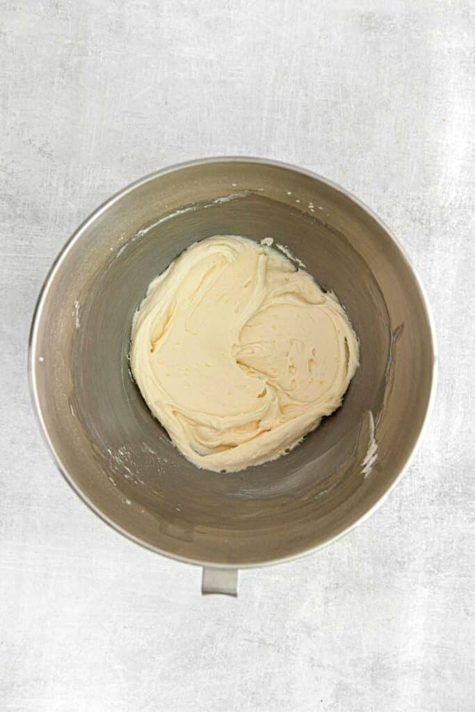 Whipped lemon curd frosting in the metal bowl of a stand mixer.