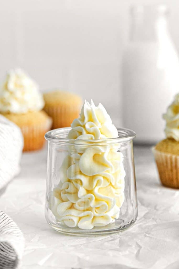 Small glass jar with piped swirls of luscious vanilla buttercream frosting for cakes and cupcakes.