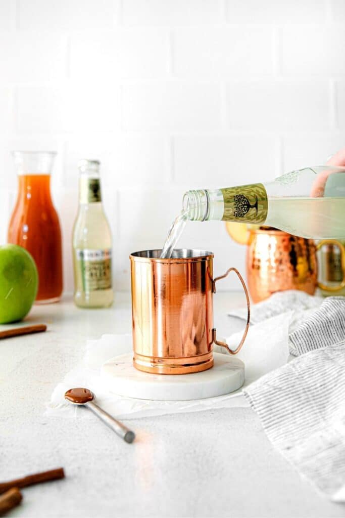 Caramel vodka being poured into a Moscow mule mug.