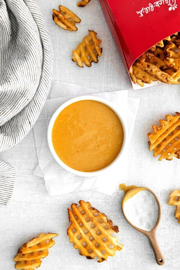 A bowl of homemade Chick-Fil-A sauce next to genuine CFA waffle potato fries for dipping.