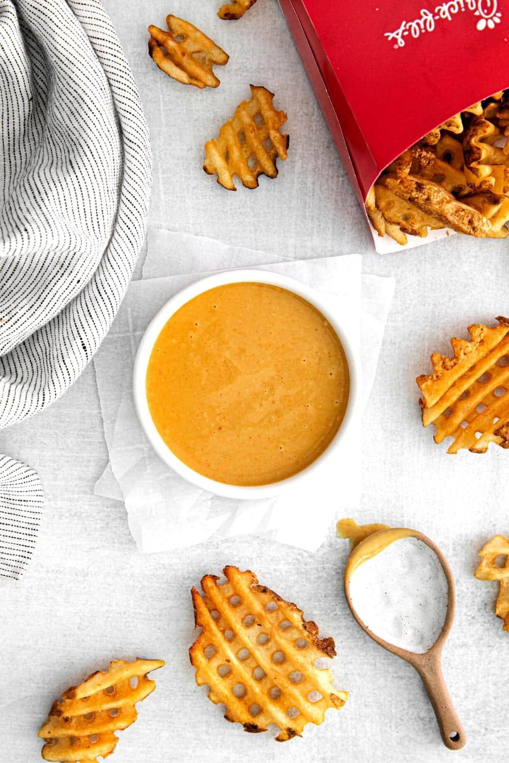 A bowl of homemade Chick-Fil-A sauce next to genuine CFA waffle potato fries for dipping.