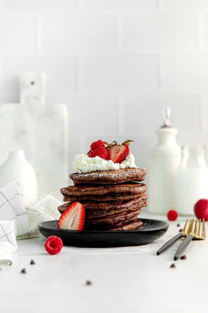Stack of copycat IHOP Chocolate Chocolate Pancakes topped with strawberries and whipped cream.