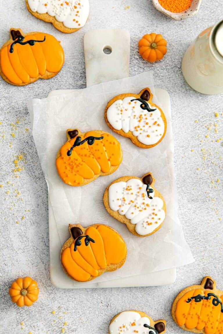 Cut-out pumpkin sugar cookies artfully decorated with orange, white and black royal icing.
