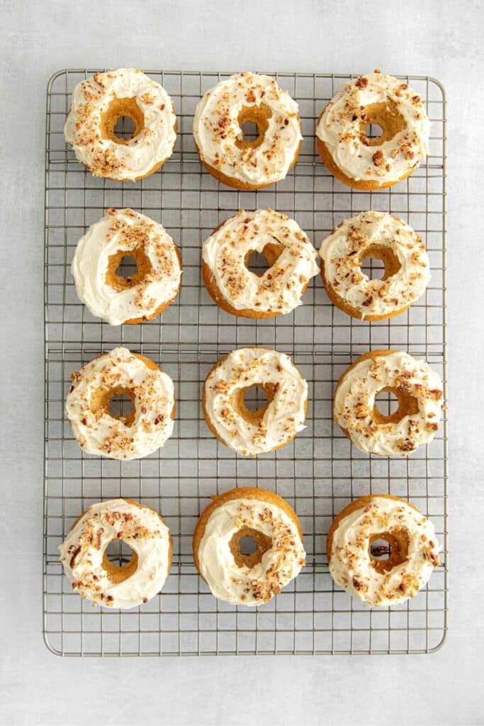 One dozen frosted maple donuts on a wire rack.
