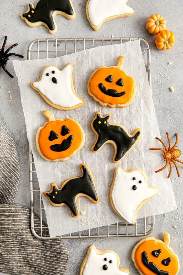 Cut-out Halloween sugar cookies decorated with royal icing: Jack-o'-lanterns, black cats and ghosts.