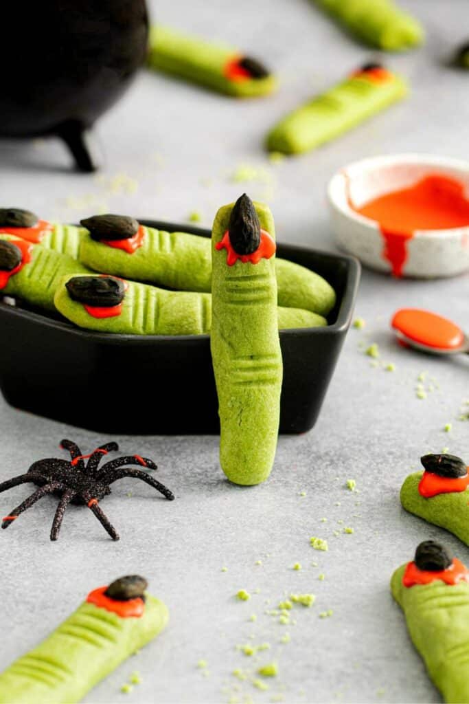 Witch fingers on a dessert table next to a black caldron and spider.