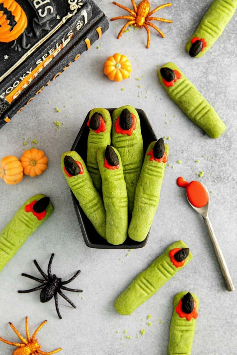 Witch finger cookies: green-tinted shortbread shaped like fingers with red nail beds and black almond nails.