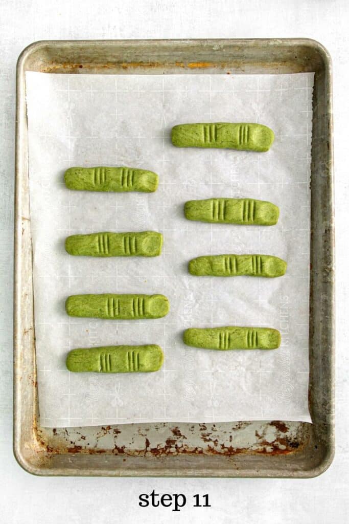 Eight witch fingers cooling on a parchment paper-lined baking tray.