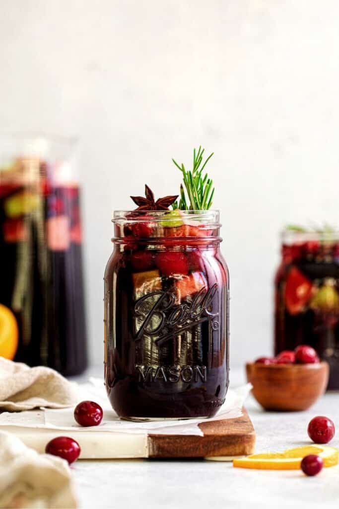 Christmas sangria on a beverage table, in a glass pitcher and in mason jars.