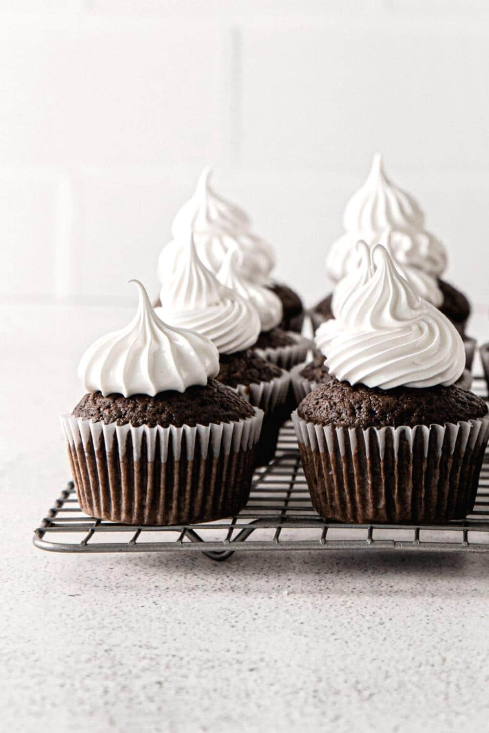 Eight chocolate cupcakes topped with marshmallow frosting.