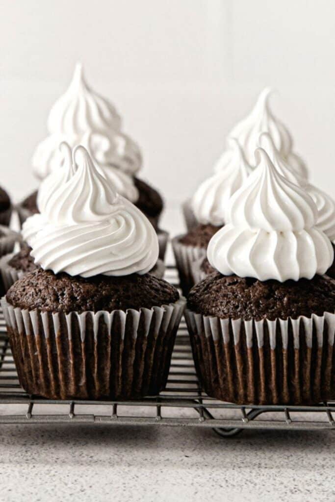 Marshmallow fluff frosting piped in tall swirls on small cakes.