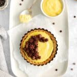 A pastry cream tartlet garnished and decorated with piped-on whipped chocolate.
