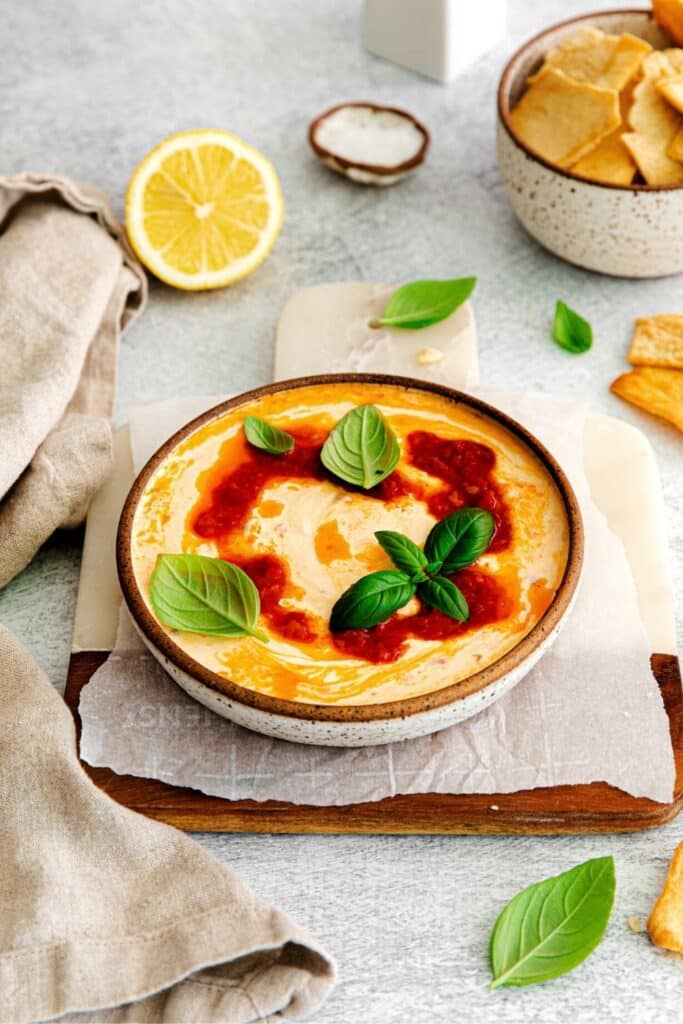 Spicy feta dip garnished with a swirl of harissa oil and fresh basil leaves.