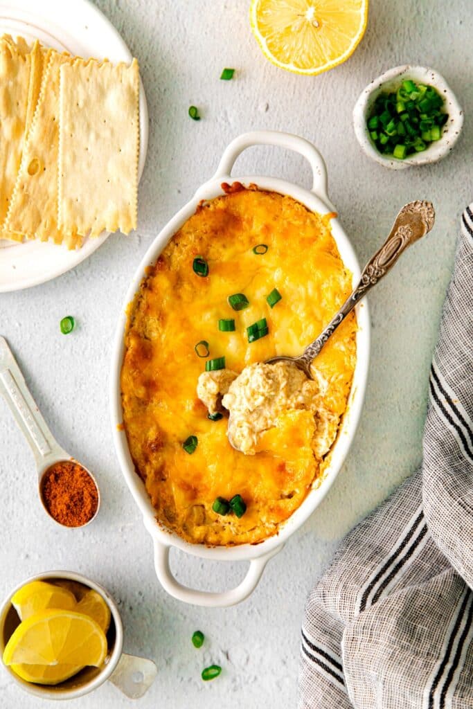 A spoonful of cheesy Cajun crab dip hot out of the oven with a green onion garnish.