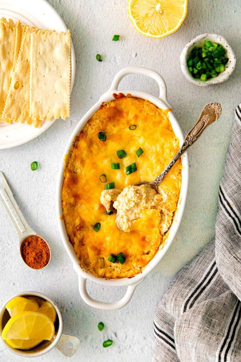 A spoonful of Cajun crab dip hot out of the oven with melty cheese and a green onion garnish.