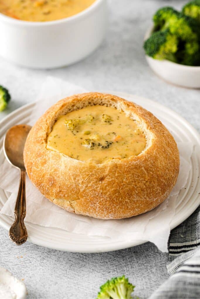 Panera broccoli cheddar soup in a bread bowl with a silver soup spoon.