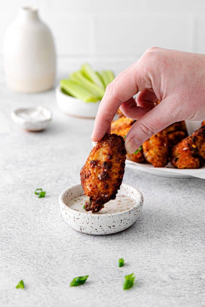Dry rub chicken wing being dipped into ranch dressing.