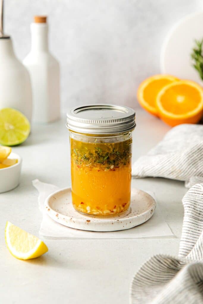 Authentic Mexican chicken marinade in a mason jar surrounded by fresh ingredients for the mixture.