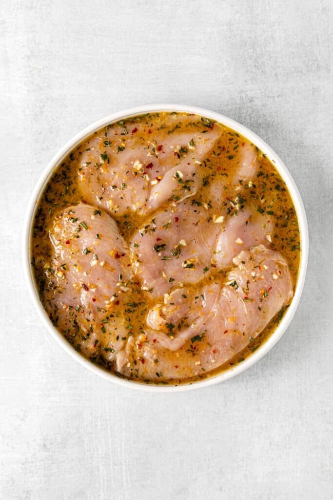 Boneless, skinless chicken breasts in a bowl of Mexican citrus chicken marinade.