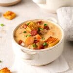 Individual serving of cheeseburger soup garnished with crispy bun croutons.