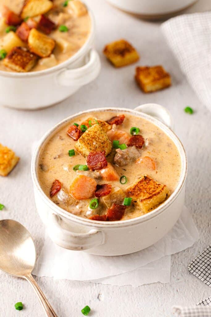 Single serving of bacon cheeseburger soup garnished with green onions, bacon bits and bun croutons.