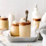 A silver spoon inside a small dessert jar of butterscotch pudding with salted caramel and whipped cream.