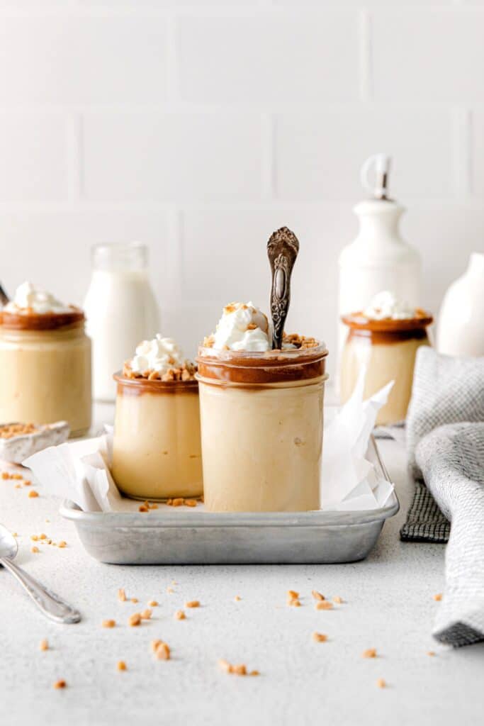 A silver spoon inside a dessert jar filled with butterscotch pudding.