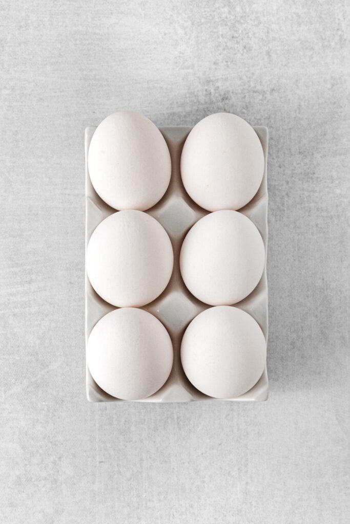 6 large eggs in a light-gray ceramic egg holder.
