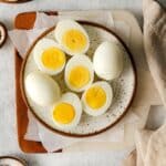 Air fryer hard boiled eggs on a plate. Some whole, some halved, yolk side up.