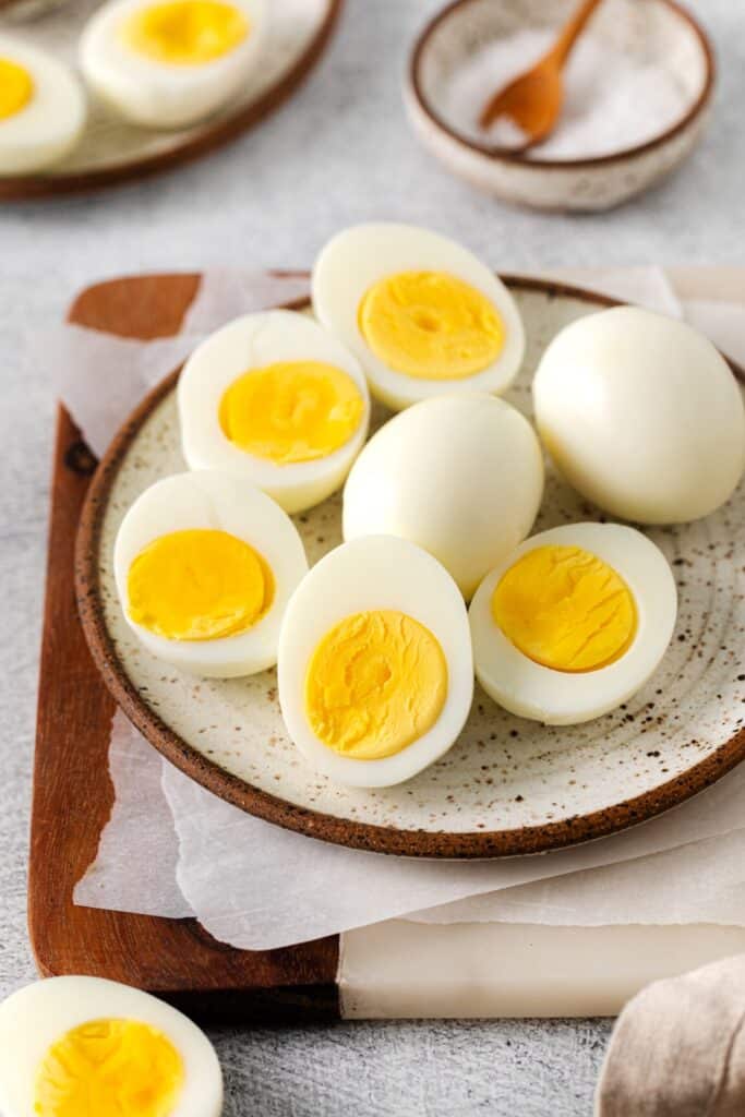 Perfect air fryer hard boiled eggs on a serving plate atop a marble/wooden board.