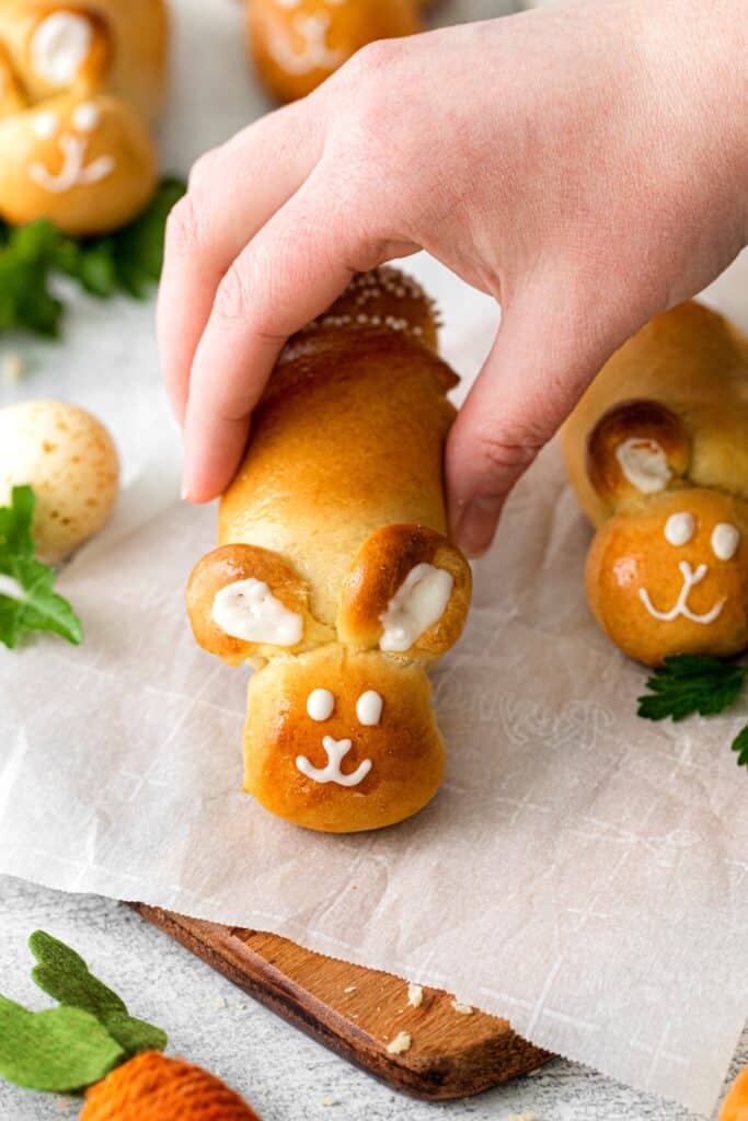 A hand reaching for an Easter bunny bread roll.