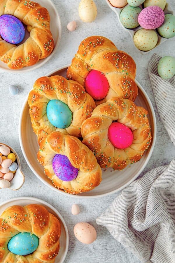 Small braided loaves of Italian Easter bread with a dyed egg in the center of each.