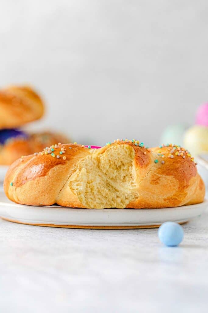 A bite taken out of Easter egg bread to reveal its tender fluffy texture.