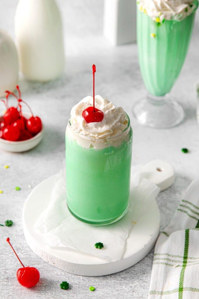 Green St. Patrick's Day milkshake topped with whipped cream and a stemmed maraschino cherry.